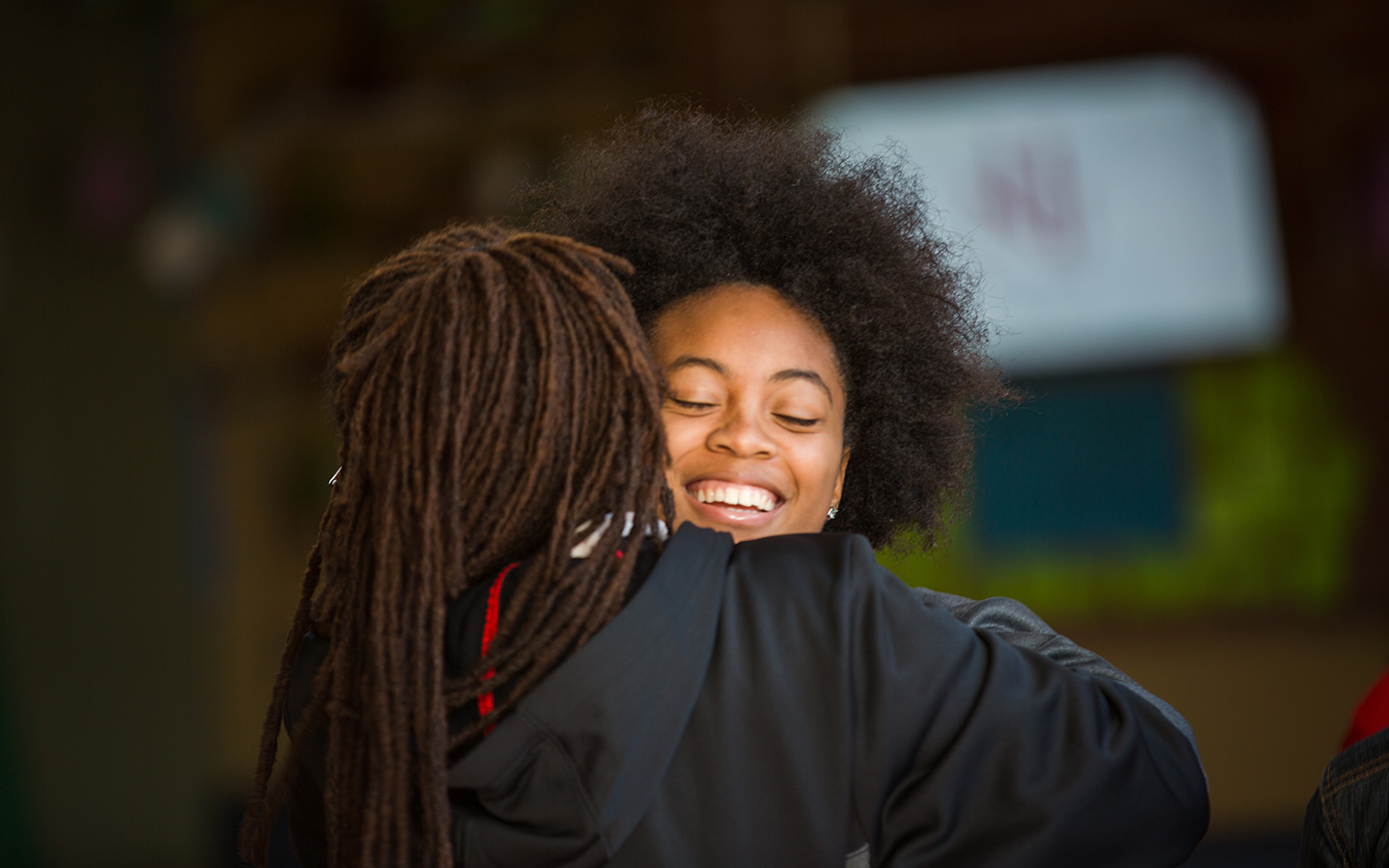Two HNU students hugging after graduation ceremony